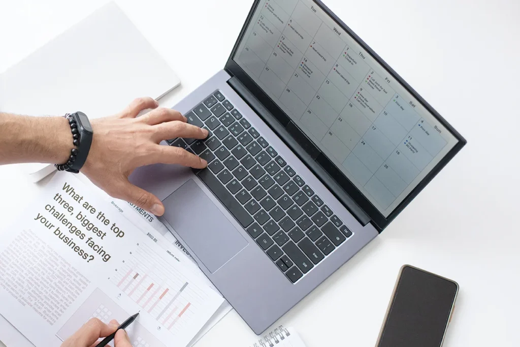 A hand typing on a laptop on a white desk, showing the concept of content marketing